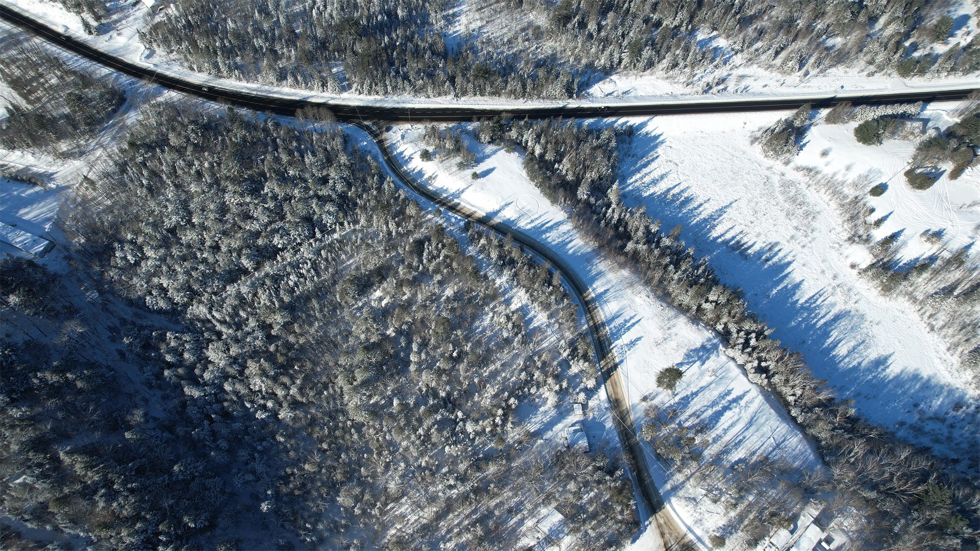 Aerial view of roads winding through a snow-covered northern forest